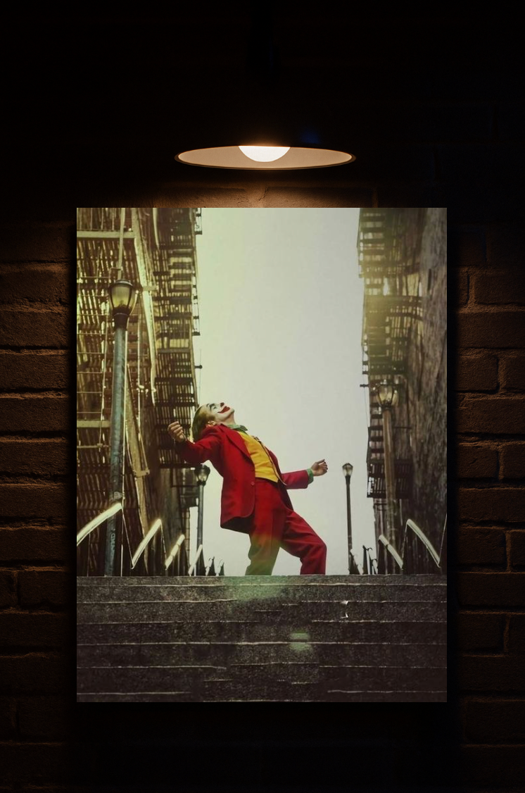 Joker in a red suit standing on a ledge with a cityscape background, framed against a brick wall printed on velvet